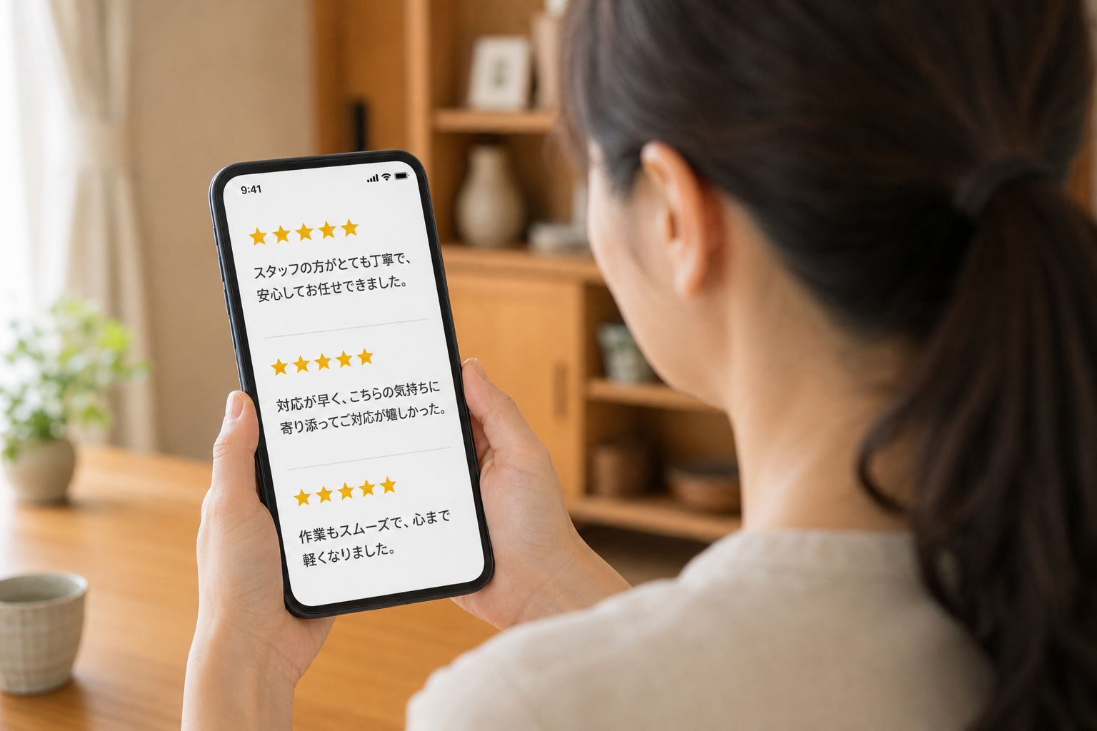 背中越しにスマートフォンの口コミ評価画面を確認している様子